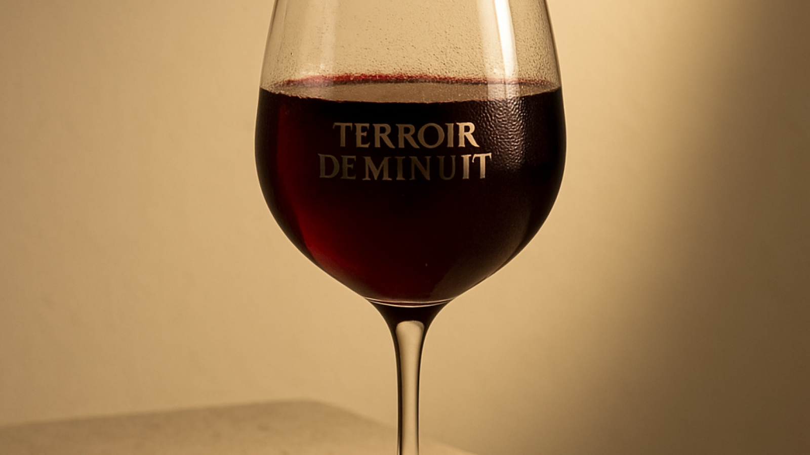 Verre de vin rouge rempli, robe grenat profond, ambiance dégustation luxe
